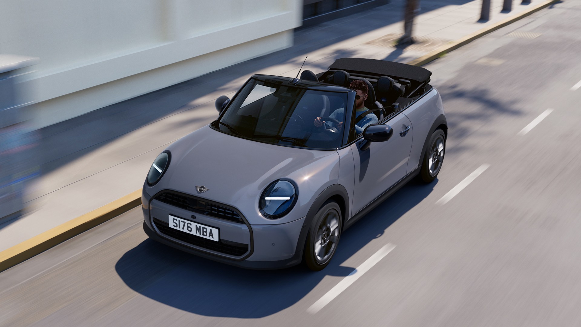 The new MINI convertible is cruising along a road, highlighting its stylish features and open-top design.